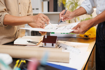 
Two people are working on a house plan design. They are using various tools, working with the...