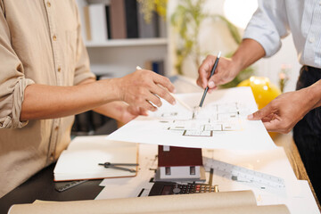 
Two people are working on a house plan design. They are using various tools, working with the...