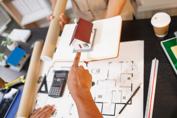 
Two people are working on a house plan design. They are using various tools, working with the...