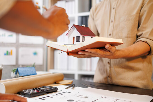 Two people are working on a house plan design. They are using various tools, working with the plan, and reviewing a house model to verify the accuracy of their work in the workplace.
- Powered by Adobe