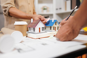 
Two people are working on a house plan design. They are using various tools, working with the...