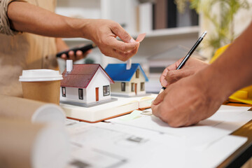
Two people are working on a house plan design. They are using various tools, working with the...
