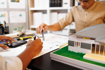 
Two people are working on a house plan design. They are using various tools, working with the...