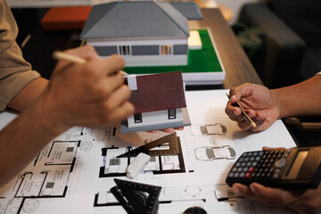 
Two people are working on a house plan design. They are using various tools, working with the...