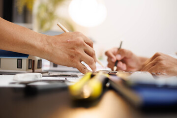 
Two people are working on a house plan design. They are using various tools, working with the...