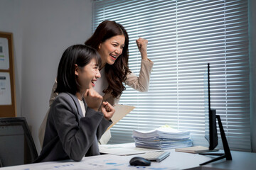 Asian businesswomen celebrating success looking at computer screen