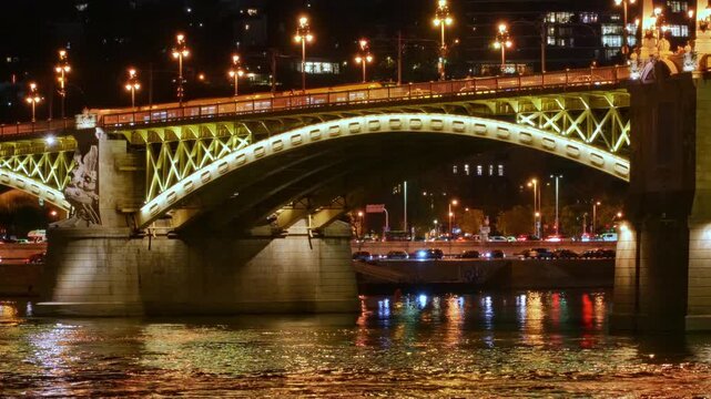 Stunning night view of the illuminated Margaret Bridge in Budapest, Hungary. The golden lights reflect beautifully on the Danube River surface, showcasing European architecture and city travel
