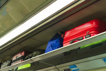 The overhead storage of an Indonesian train carriage containing suitcases and box.