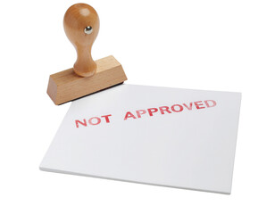 A wooden stamp beside a white card, prominently displaying the red text "NOT APPROVED.