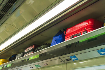 The overhead storage of an Indonesian train carriage containing suitcases and box.
