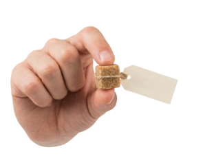 A hand holds a small, textured cube attached to a blank tag, suggesting it is an item for sale or identification.