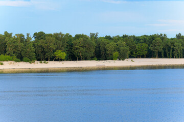 ordinary outskirts view of river side coast line sand beach along water and trees forest background area clear weather day time