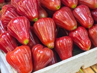 A vibrant, close-up view of fresh wax apples (also known as java apples or rose apples) displayed in a market crate.