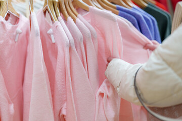 Hand selecting pink clothing in a retail store during a shopping trip on a weekend