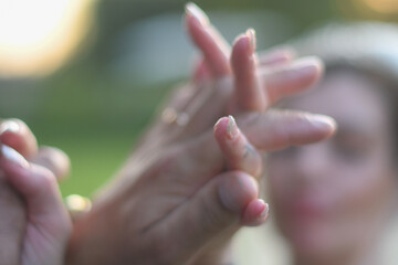 Woman's hands with manicured nails touching fingertips in sunlight