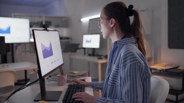 Asian woman analyzing data sales report and information sheet, comparing statistics on digital monitor, representing data analysis, overtime work, hardworking lifestyle in night office.