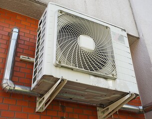 External AC condenser unit. Outdoor air conditioning unit mounted on a tiled exterior wall