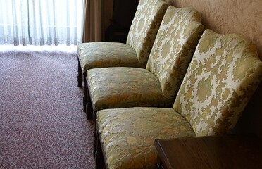 A set of three fabric-covered chairs lined up along the wall in a sunlit room