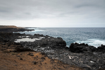Volcanic rock pools and rugged cliffs meet the Atlantic Ocean under a cloudy sky in Los Silos, Tenerife, Spain, capturing the island&rsquo;s raw and dramatic coastal beauty