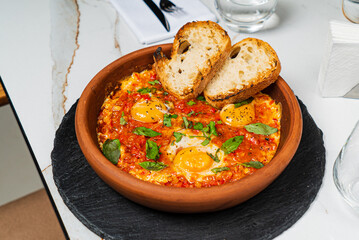 Colorful shakshuka features eggs nestled in spicy sauce, served with crusty bread and herbs