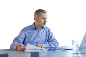 Mature businessman with beard working with documents, contracts and bills sitting at table using laptop at work on a transparent background