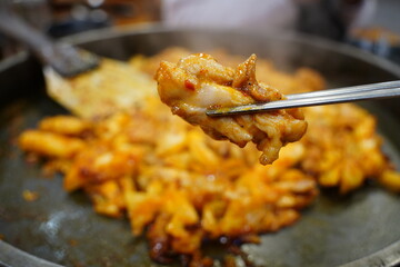 Sizzling Korean spicy stir fried chicken (Dak-galbi) with vegetables on a hot iron plate