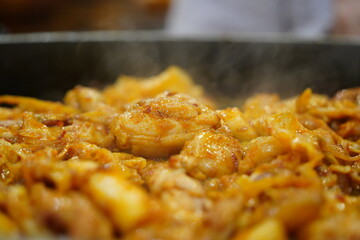 Sizzling Korean spicy stir fried chicken (Dak-galbi) with vegetables on a hot iron plate