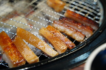 Korean style grilled pork skin sizzling on a charcoal grill, a popular anju snack