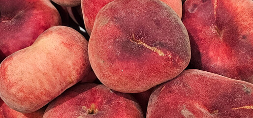 Fresh Spanish Saturn peaches, also known as donut peaches, with a rich red hue and velvety texture,...