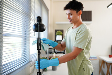 Worker in blue gloves using detergent to wipe computer screen during wet cleaning in office