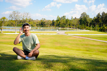 Naklejka premium Man relaxing on grass listening to music with headphones enjoying nature and peaceful summer day outside