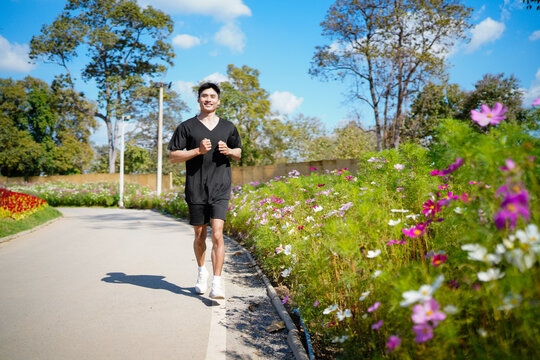 Happy and smiling asian man doing exercise and jogging or walking with relaxation for healthy in park outdoor after retirement during summer time. Health care outdoor lifestyle concept.