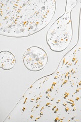 Serum fluid 24k gold gel facial cream smear, on light grey background. Beauty cosmetic product smudge, pure transparent lotion with gold particles, skin care jelly serum, top view Luxury moisturizer