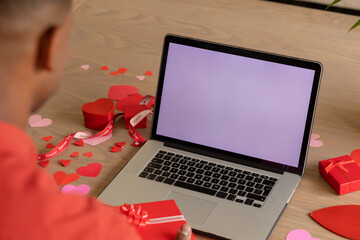 Black man with Valentine's gift on laptop video call, blank screen visible © wavebreak3