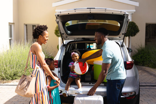African american family smiling while standing near their car outdoors
