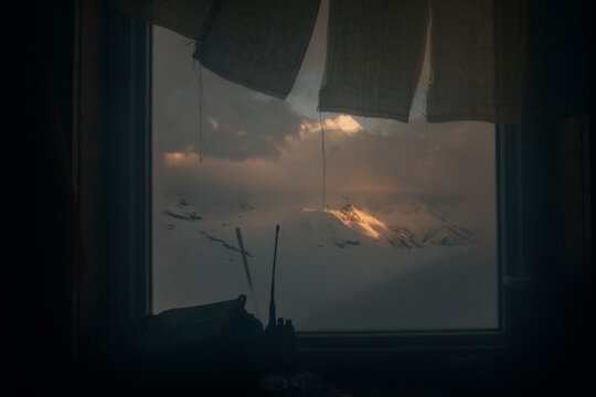 Light on a distant mountain as seen through a window of a hut.