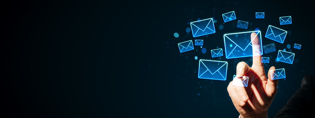 Hand touching glowing email icons on a dark background representing digital communication and online messaging concept in a modern business context.