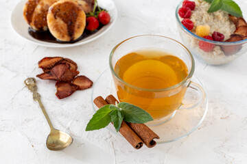 Glass cup of green tea with cinnamon and leaves of mint on a saucer.