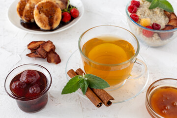 Glass cup of green tea with cinnamon and leaves of mint on a saucer.