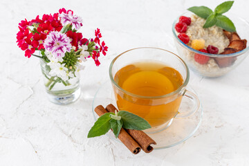Glass cup of green tea with cinnamon and leaves of mint on a saucer.