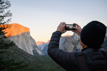 Tourist taking photos using smartphone at Yosemite Tunnel View. Yosemite National Park. California. USA.