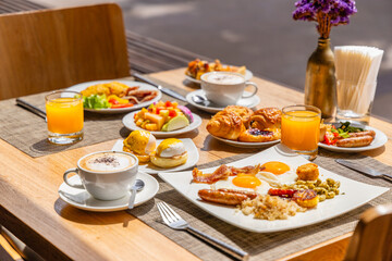 Breakfast table outdoors with eggs, bacon, juice,
