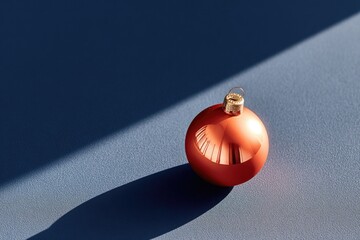 Shiny red ornament casts striking shadow on smooth blue surface