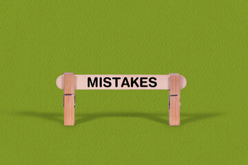 Fototapeta premium Mistakes symbol. Wooden stick anchored by Clothespins, Cool Green Background. Business and Mistakes concept with copy space