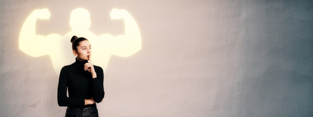 Thoughtful woman standing beside wall with glowing superhero silhouette symbolizing inner strength and self-confidence concept background.