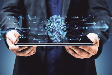 Digital fingerprint authentication symbol above tablet held by person in suit on dark background with holographic user interface graphics.