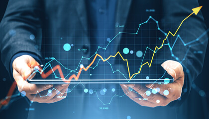 Businessman holding tablet with financial charts and upward arrow showing growth and investment...