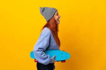 Teenager Russian skater girl isolated on yellow background laughing in lateral position © luismolinero