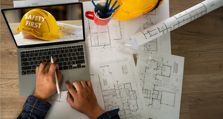 Site surveyor review design, helmet yellow placed near building where architect follow rule in manufacturing at safety workplace to prevent first accident.