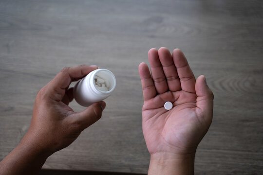 Close-up of hands pouring pills into palm from a medicine bottle, representing medication use, healthcare treatment, daily dosage, and responsible drug consumption Medicine and health care concept